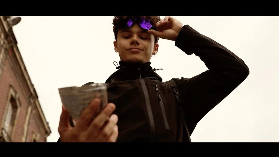 Le héros soulève ses lunettes en tenant un emballage ramassé, film WasteBuster